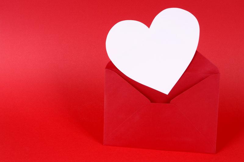 红色背景上的红色信封里的白色心形卡片