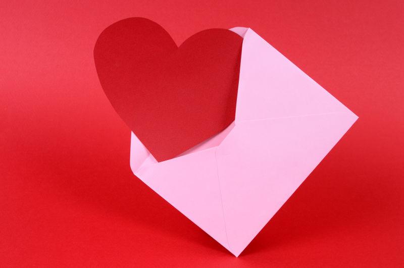 红色背景下的粉色信封里的红心卡片