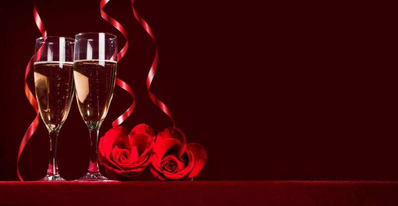 红色木桌上的玫瑰花和香槟酒杯