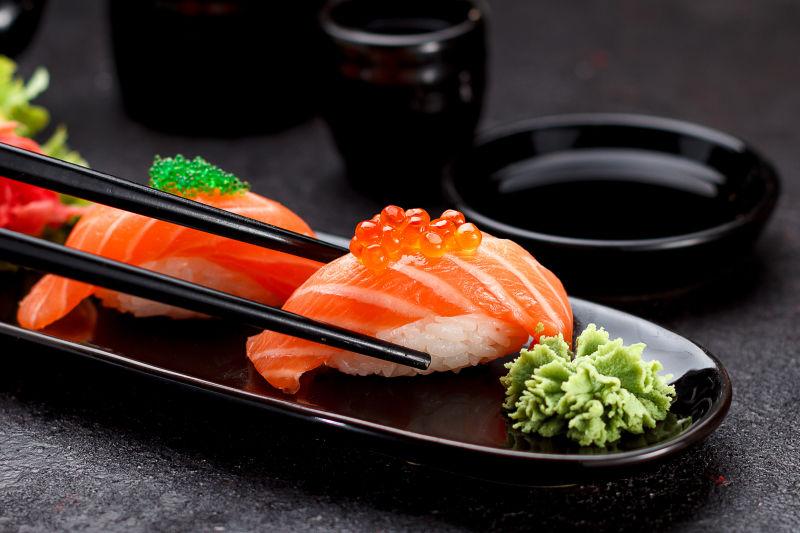 三文鱼寿司在黑板上用筷子夹住