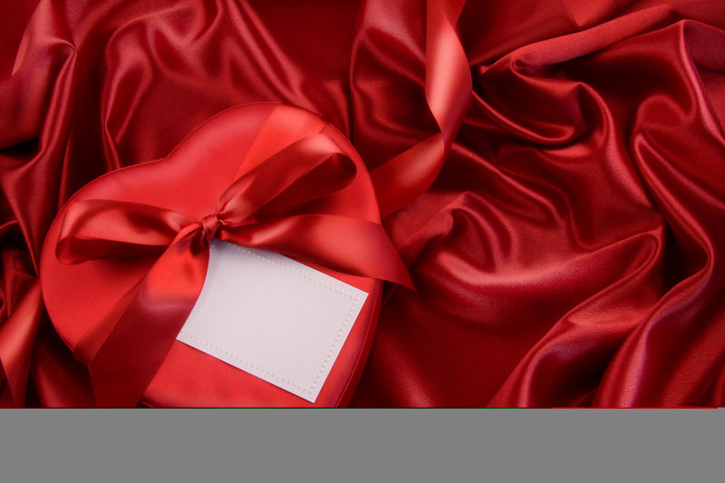 红色丝绸背景中的卡片和礼物