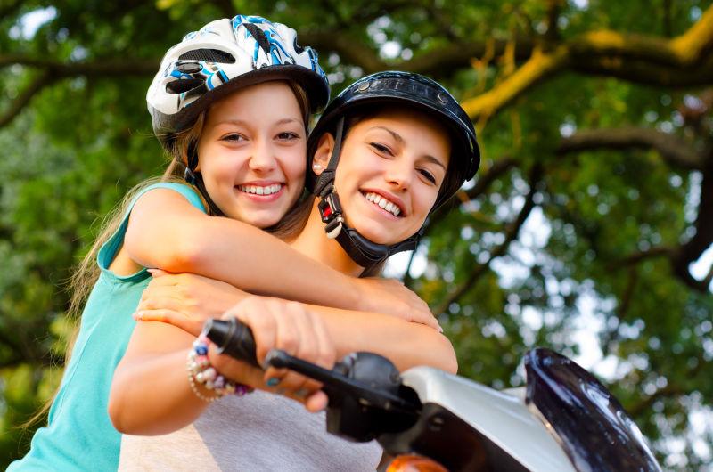两个十几岁的女朋友骑滑板车