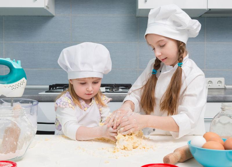 厨师制服上的两个小女孩揉搓面团