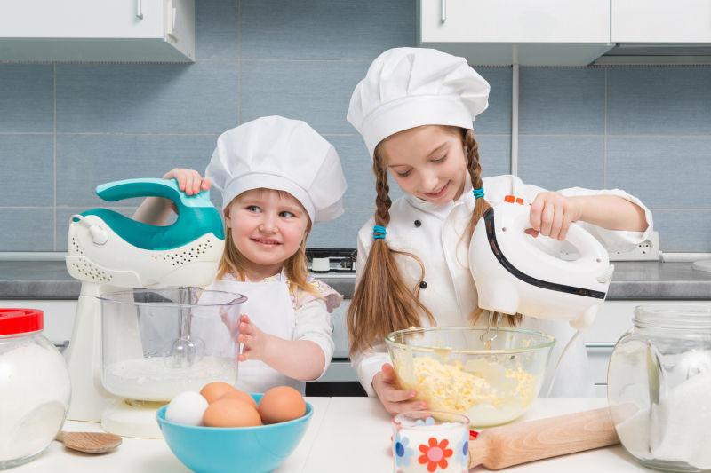 在厨房的穿着厨师制服两个快乐的孩子