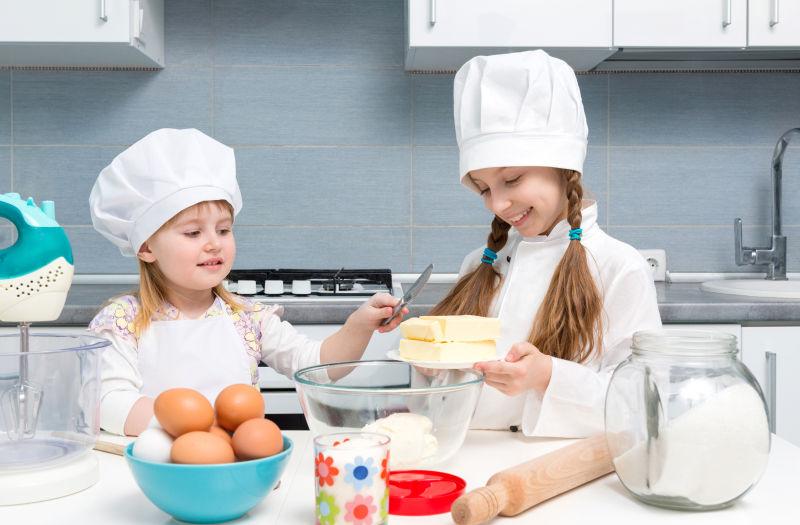 在厨房里切蛋糕的两个快乐的孩子