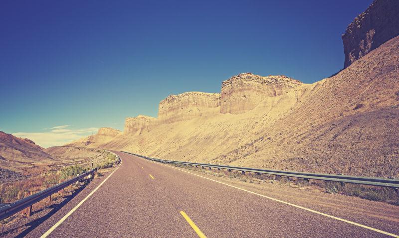 蓝天下山里的老式色调的犹他州乡村公路
