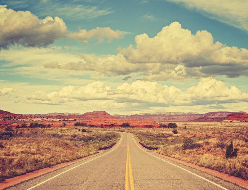 蓝天白云背景下沙漠中的无尽的乡村公路
