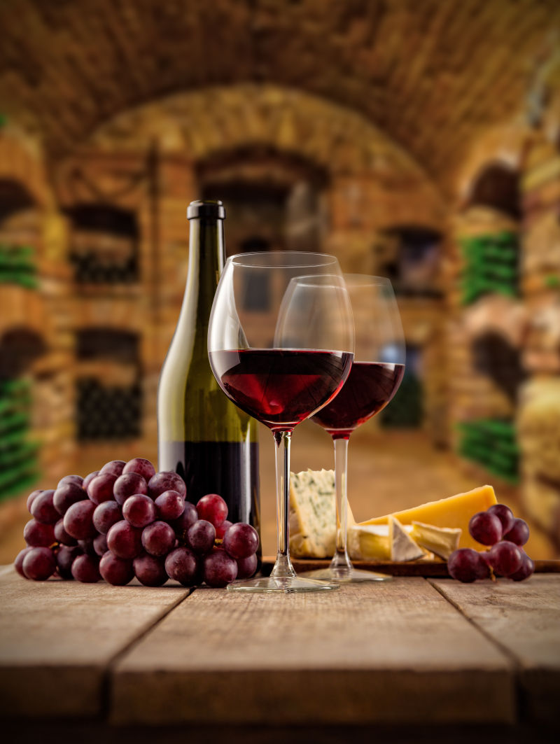 旧木桌上的红葡萄酒和葡萄