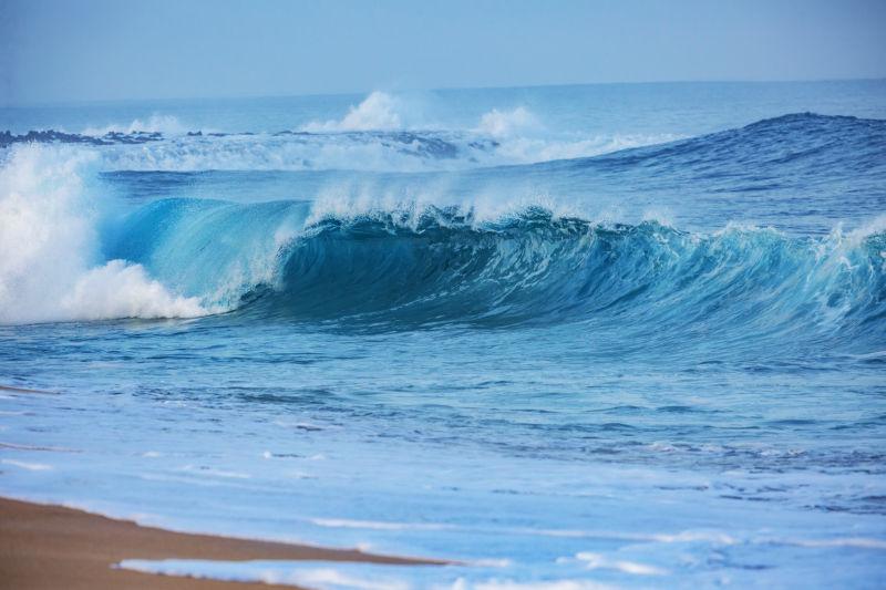在淡蓝色海洋中翻滚的巨大的海浪