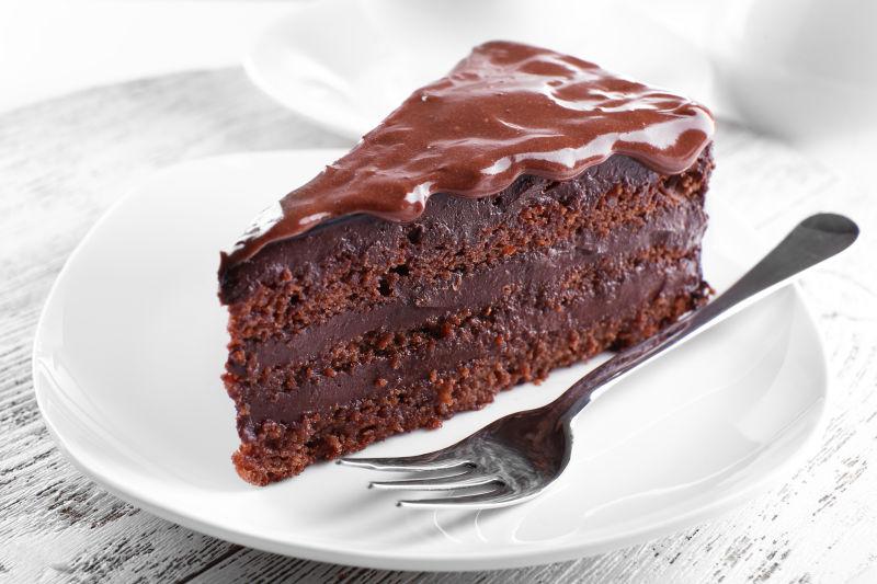 木桌上白色盘子里的美味巧克力蛋糕