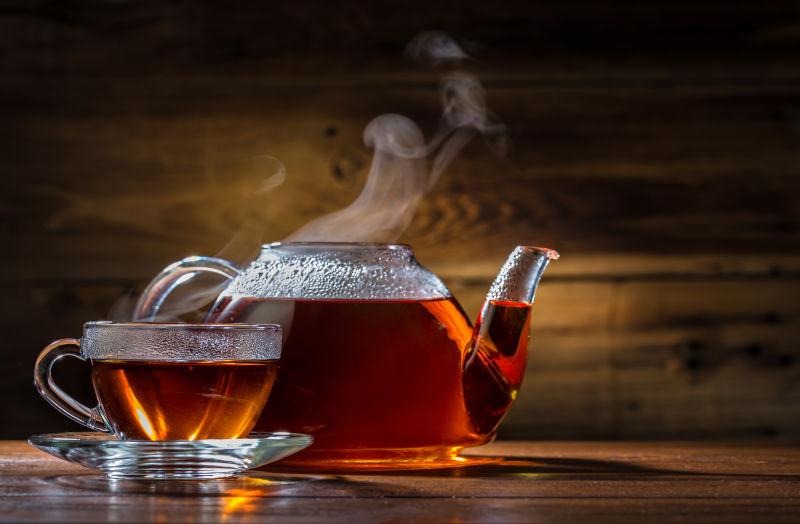 木制背景下的玻璃茶壶和杯子红茶