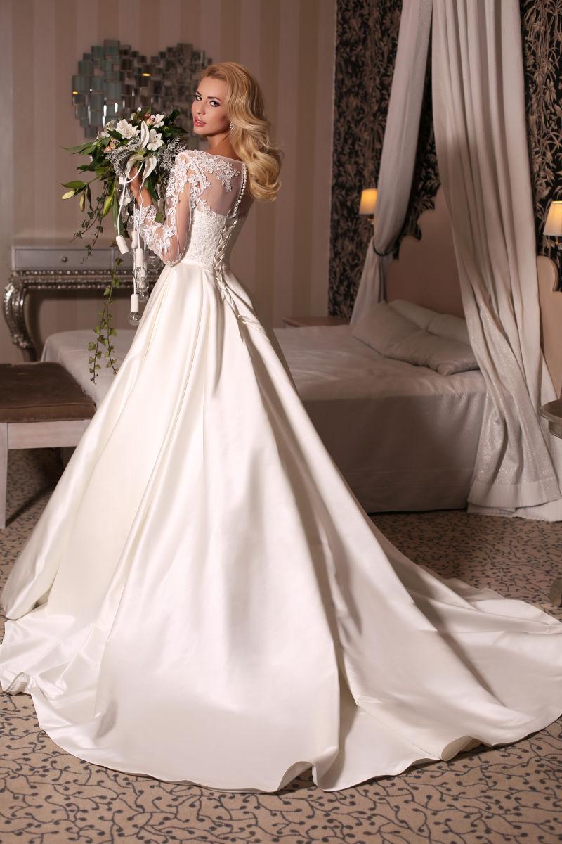 美丽的新娘金发穿着豪华婚礼礼服与碧瑶拿着花束