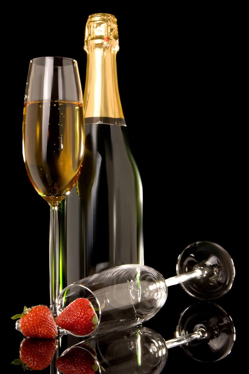 黑色背景上的草莓与香槟酒酒杯酒瓶