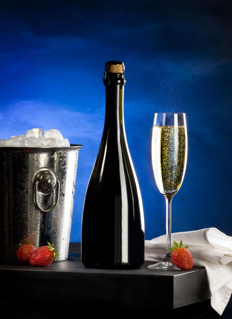 蓝色背景下的香槟酒草莓和冰桶
