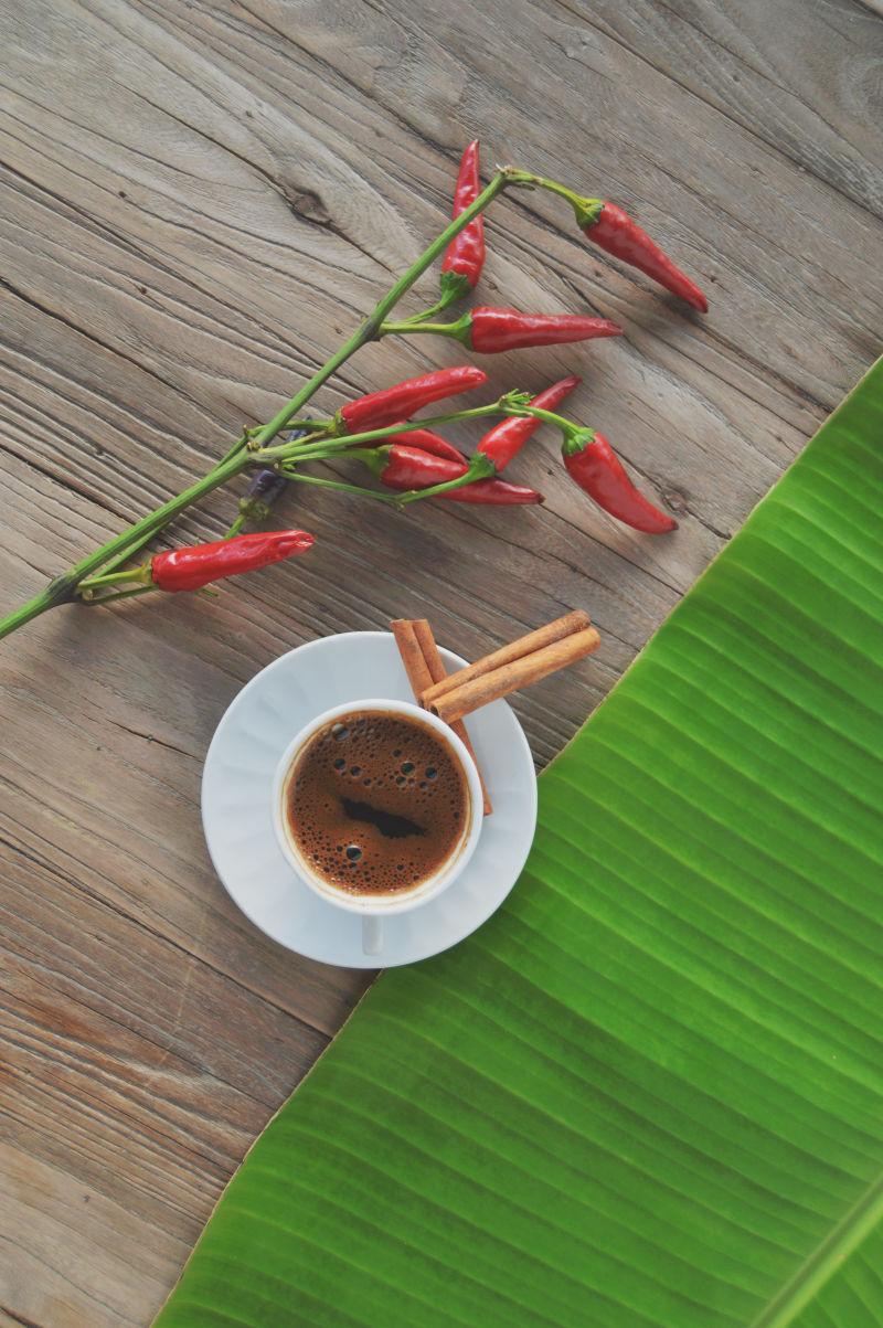 木桌上的咖啡和辣椒树叶