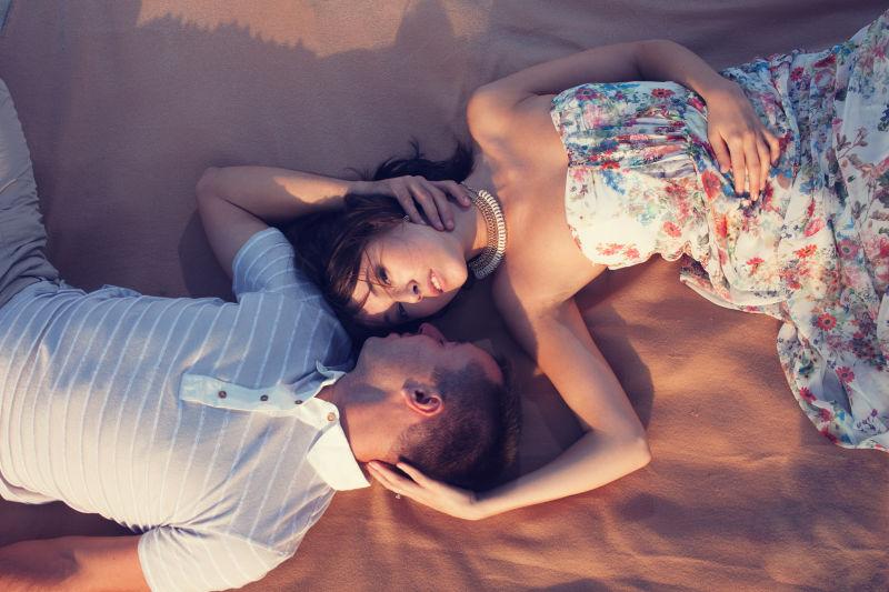 美丽的情侣躺在沙滩上亲吻