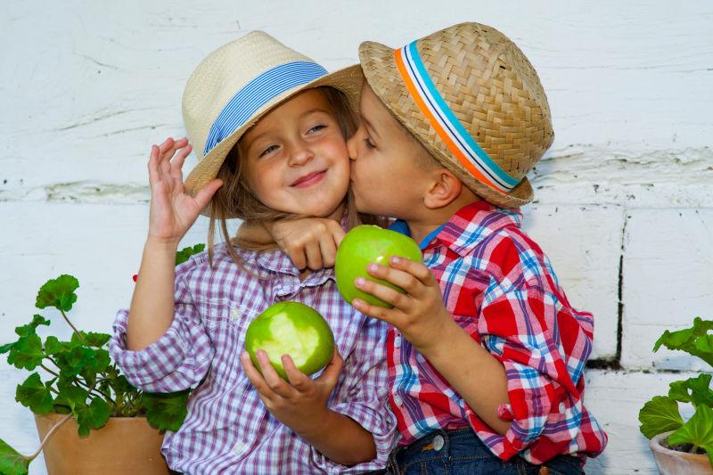 戴帽子的情侣儿童拿着苹果