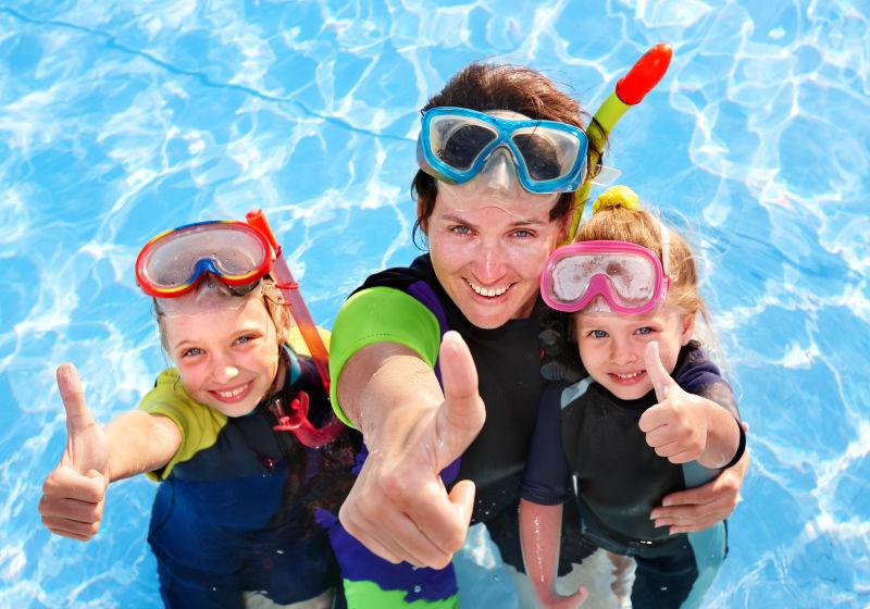 在游泳池里学习浮潜的母亲和孩子们