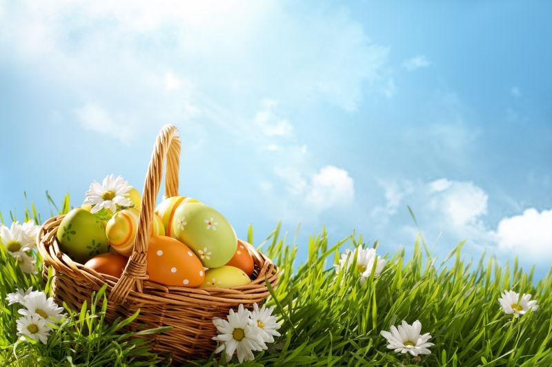 蓝天下的一篮子复活节彩蛋在绿草地上