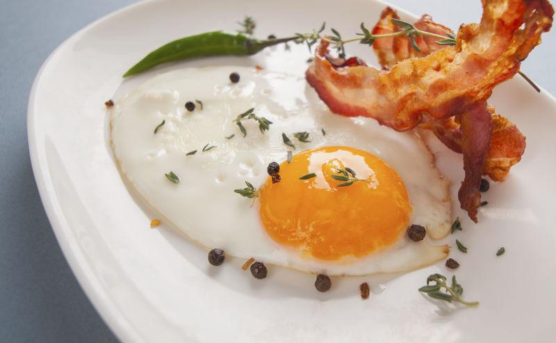 白色盘子里的煎蛋和熏肉