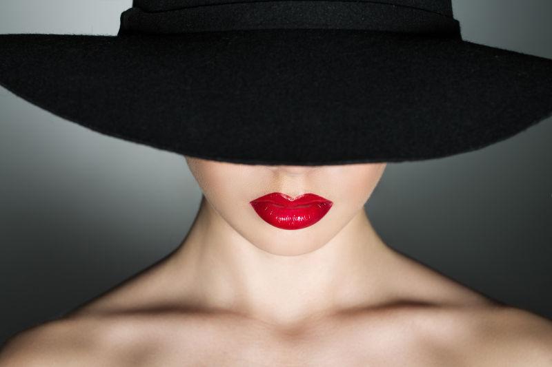 灰色背景下带着黑色帽子的红唇美女