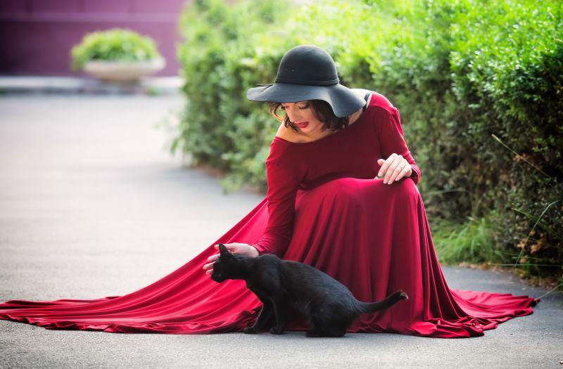 穿着红色晚礼服和黑色猫的女人