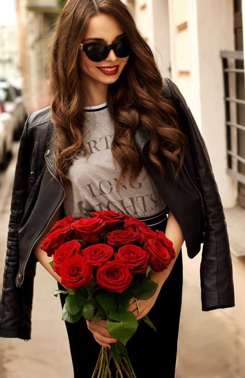 拿着红色玫瑰花的年轻时尚女人