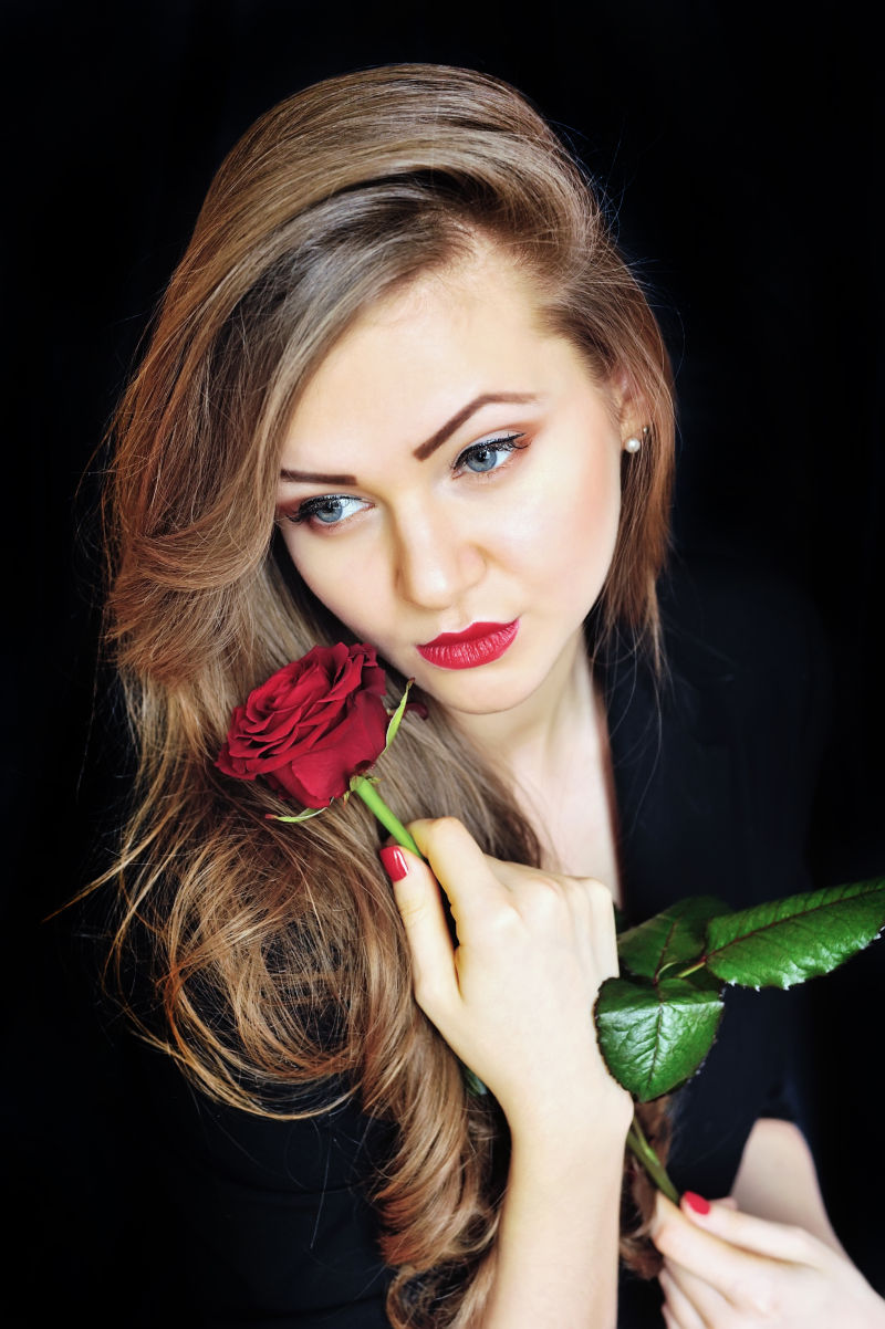 手拿一枝玫瑰花的美丽女人