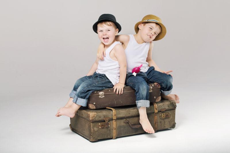 两个可爱的小兄弟坐在手提箱上