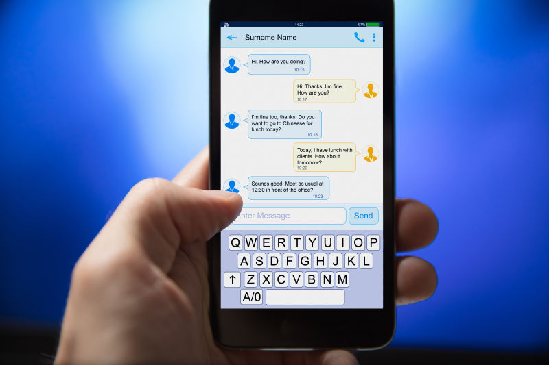 在蓝色背景下从手机发送短信的人