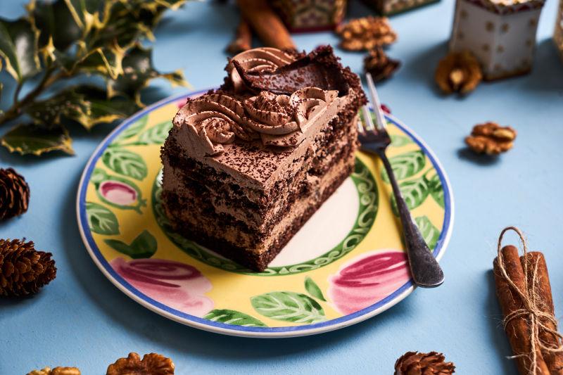 蓝色背景下圣诞节盘子里的美味的巧克力蛋糕