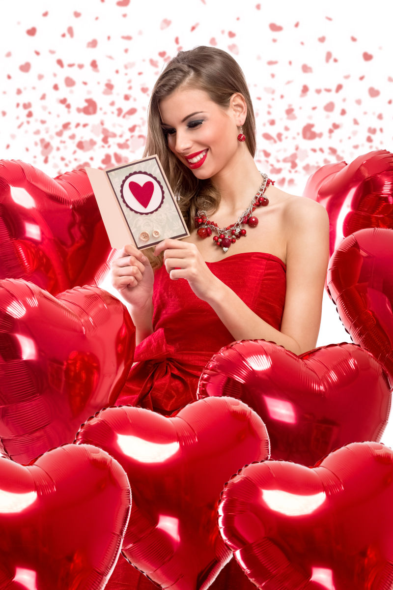 情人节女孩在心形红色气球中看卡片