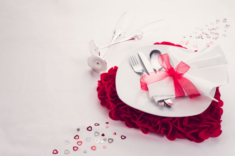 白色背景下红色心形玫瑰和餐具