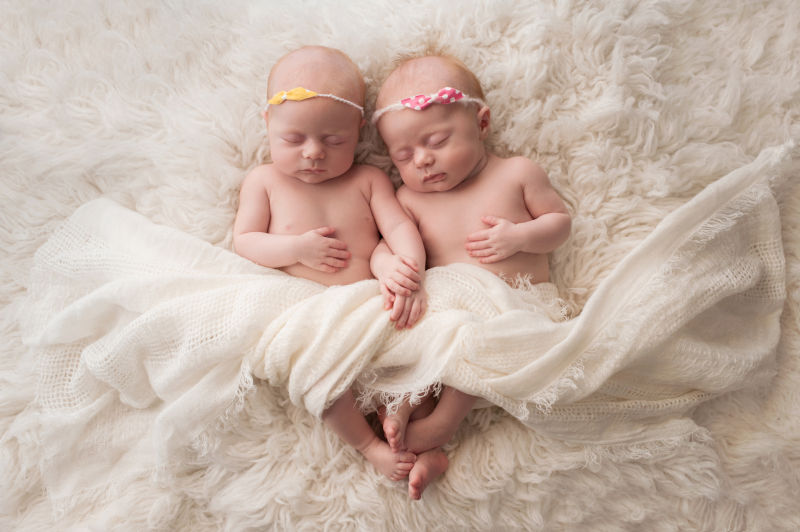 躺在白色地毯上睡觉的两个婴儿
