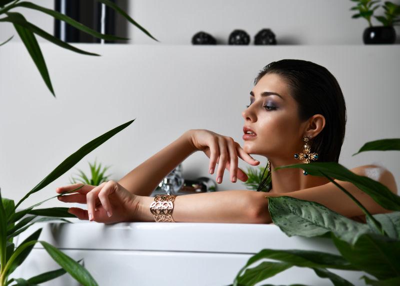植物背景下戴着首饰趴在浴缸里的性感美女