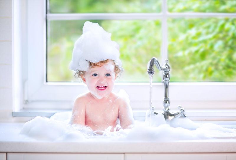 滑稽的小女孩带着卷曲的毛发在水池里洗澡