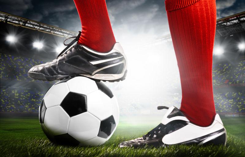 足球运动员的腿和脚下的足球