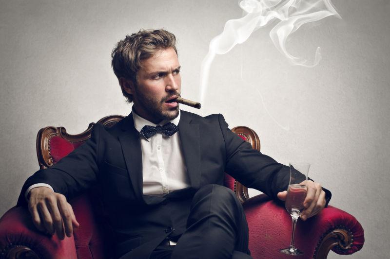 坐在红色沙发上男人抽着雪茄