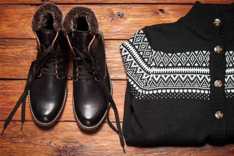 木桌上的黑褐色毛衣和皮靴
