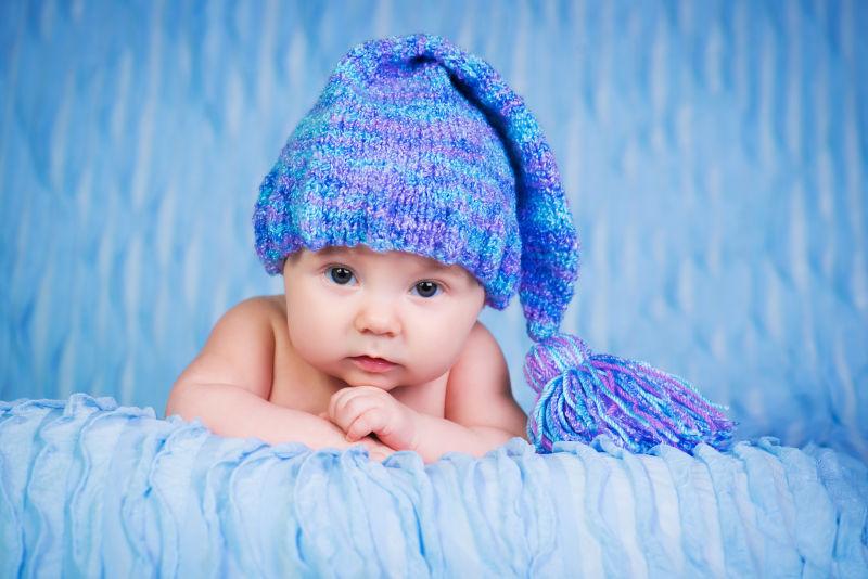 新生儿戴在蓝色背景的针织帽上