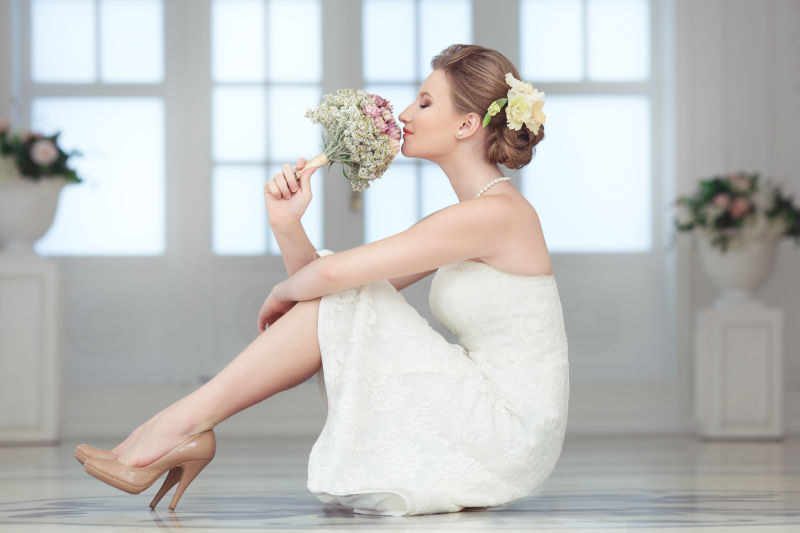漂亮的新娘穿着白色礼服坐在地板上