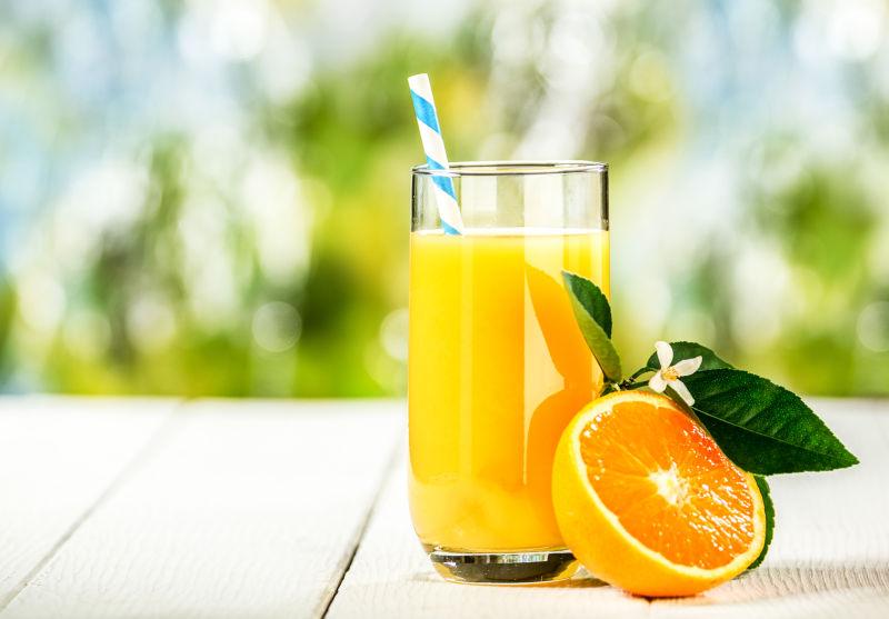 一杯鲜榨的鲜榨橙汁摆在一个户外木制野餐桌上