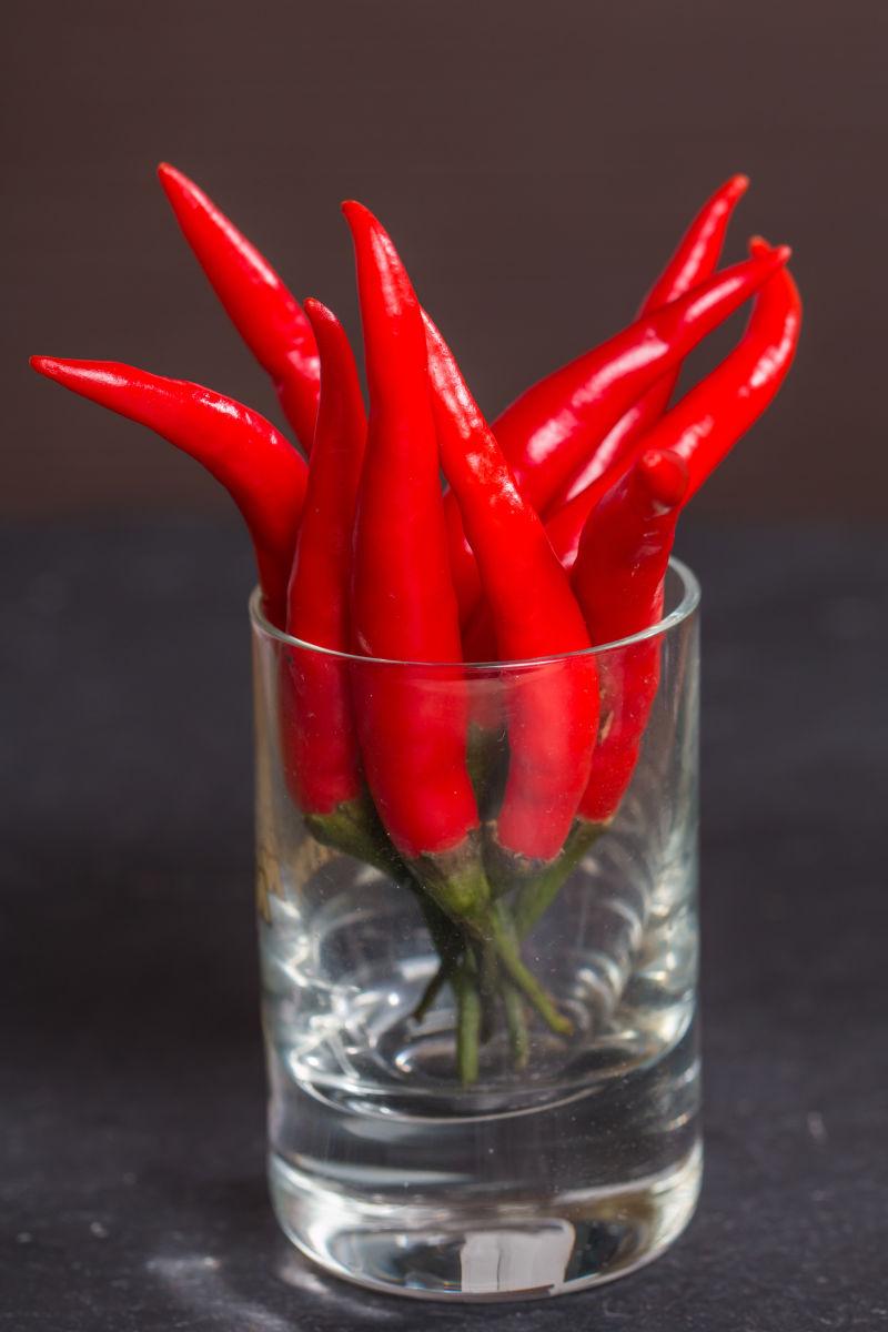 黑色背景上透明玻璃杯中的红色辣椒