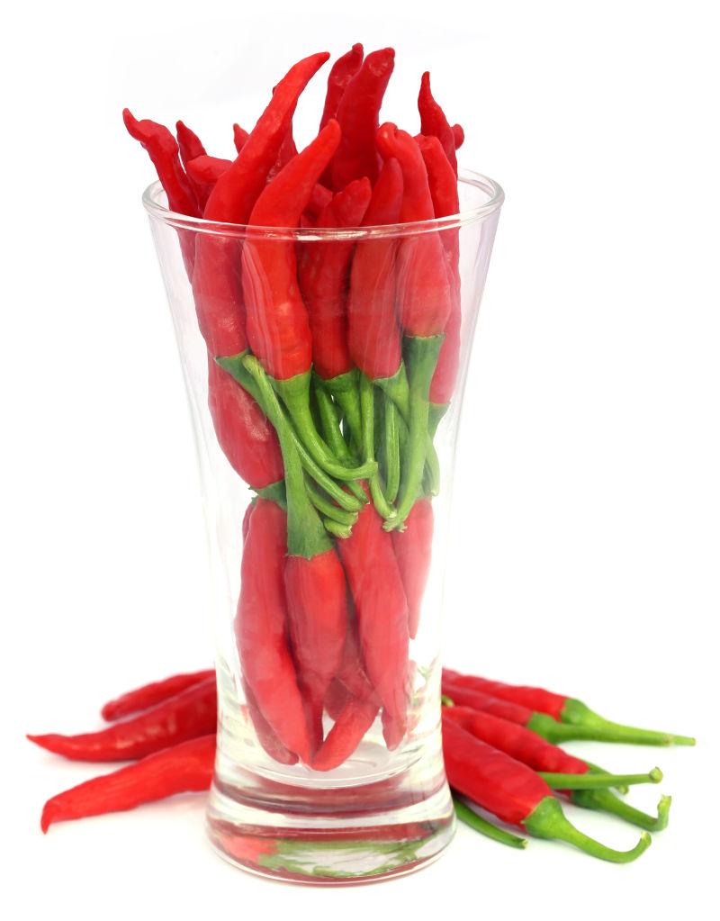 白色背景下放在玻璃杯里面和外面的红辣椒