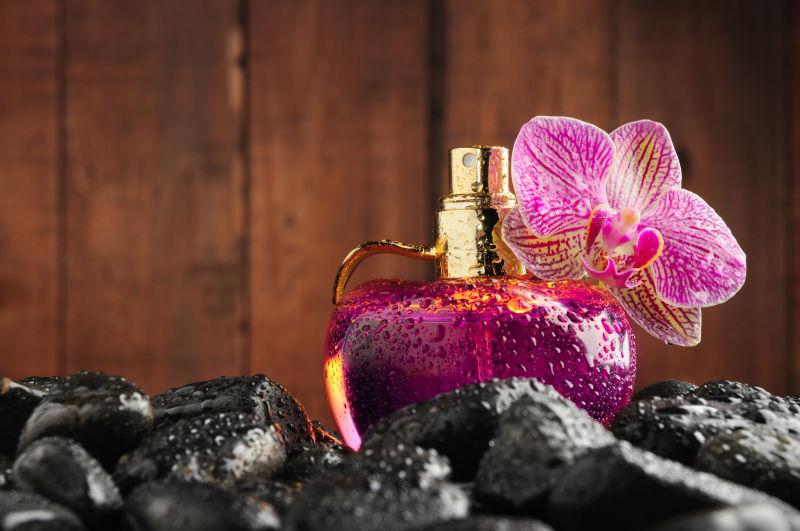 鹅卵石上的紫色香水瓶