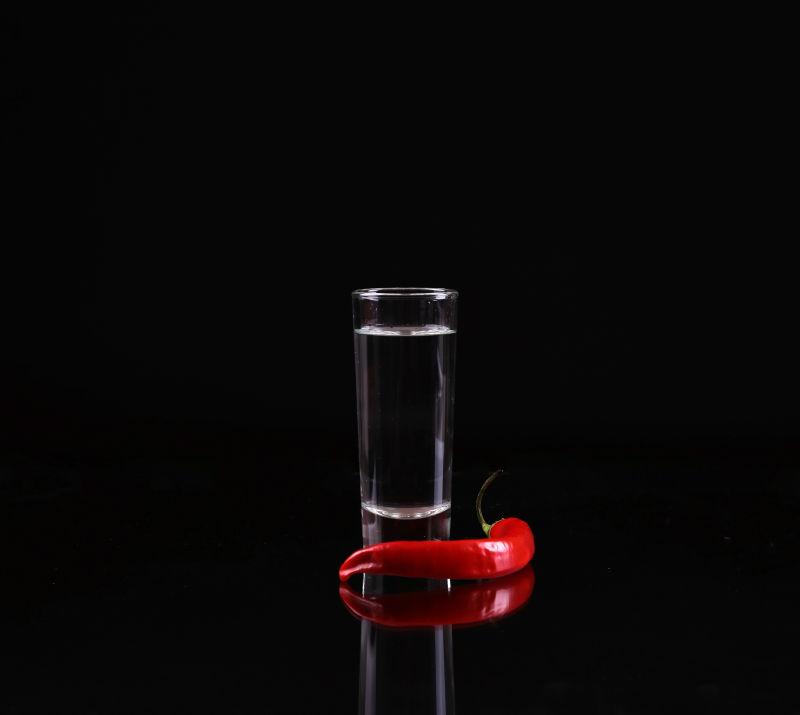 黑色背景上的酒杯和红辣椒