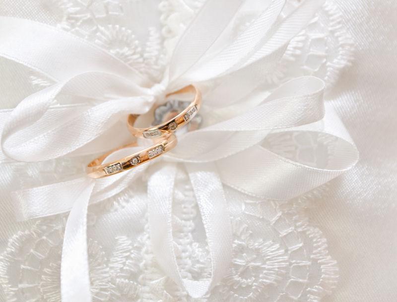 白色丝绸上的黄金钻石结婚戒指