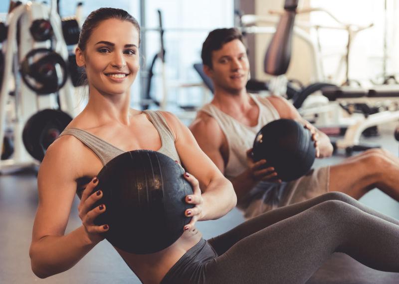 有魅力的年轻肌肉发达的男人和女人在健身房锻炼