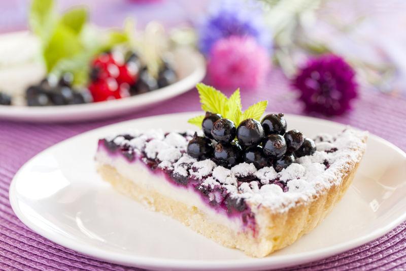 紫色桌上白色盘子里的浆果蛋糕