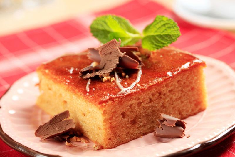 红色格子布上白色盘子里的蜂蜜蛋糕和巧克力薄片